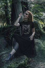 Acusinkt Lilith unisex t-shirt in zwart gedragen door een vrouw in een donker bos