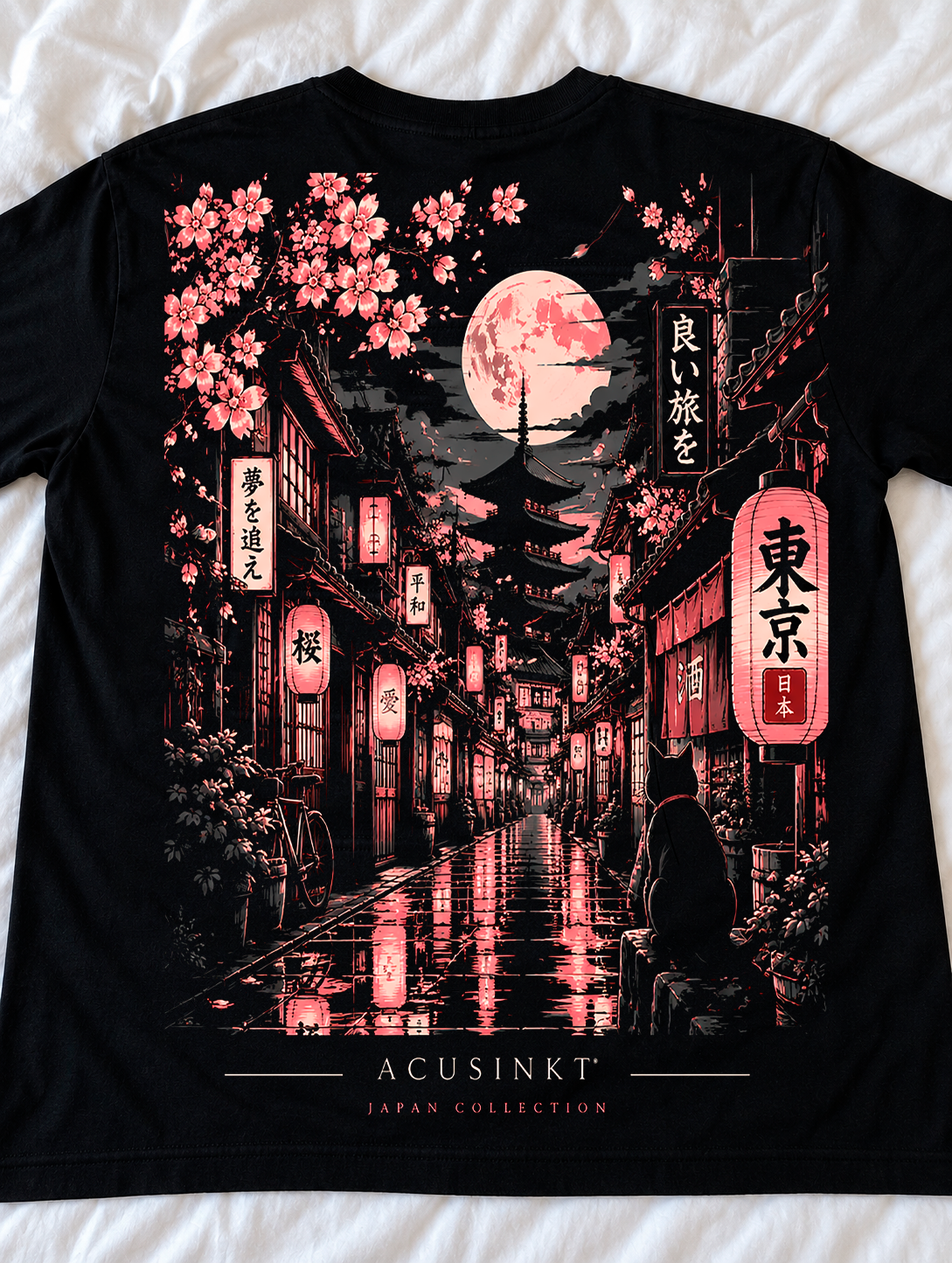 Detail van de achterkant van het zwarte Sakura Street T-shirt op een wit laken: sakura-takken, volle maan, pagode, gloeiende lantaarns en een kat in roze en crème tinten